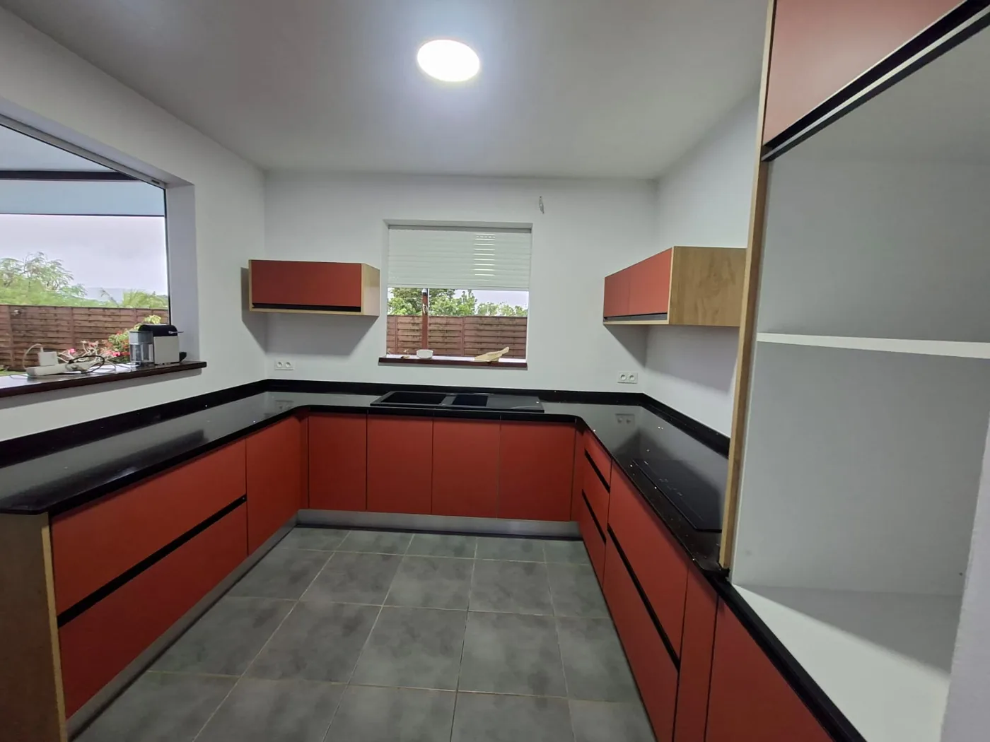 Cuisine terracotta avec plan de travail noir et meubles hauts assortis